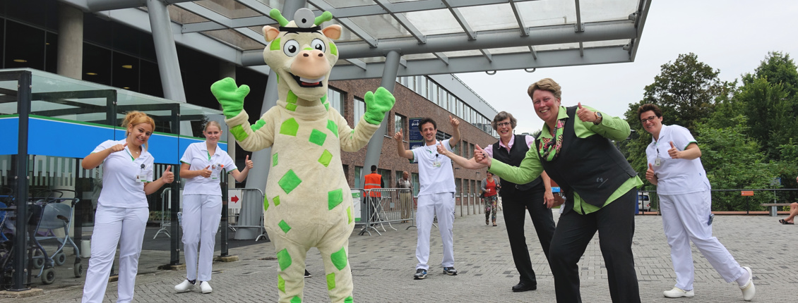 Freek de Giraffe en het team van de stichting voor de ingang van het ziekenhuis